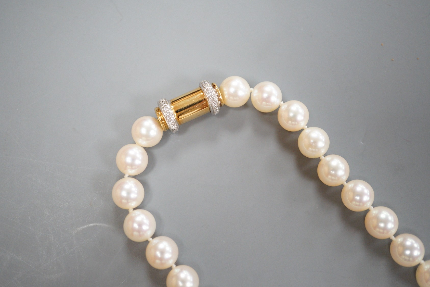 A cased modern single strand Akoya cultured pearl necklace, with diamond chip set 750 yellow metal barrel shaped clasp, retailed by Musson, 43cm, gross weight 59 grams